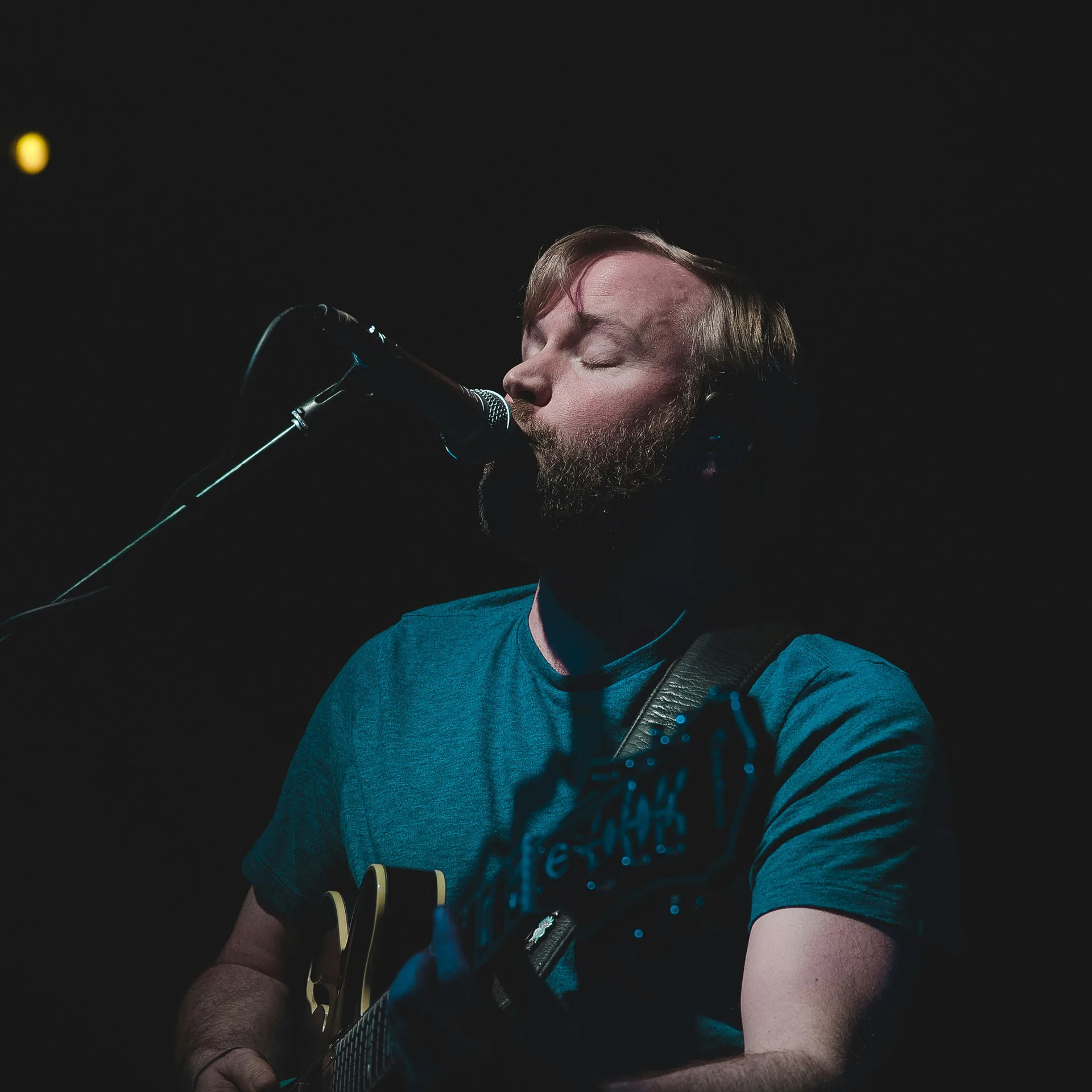 Musiker med gitarr som sjunger i en mikrofon